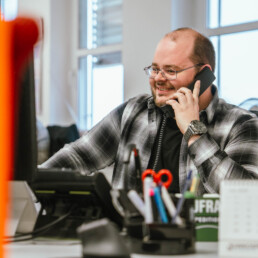 Spedition Mäuler Mitarbeiter der Spedition Mäuler telefoniert lächelnd an seinem Schreibtisch